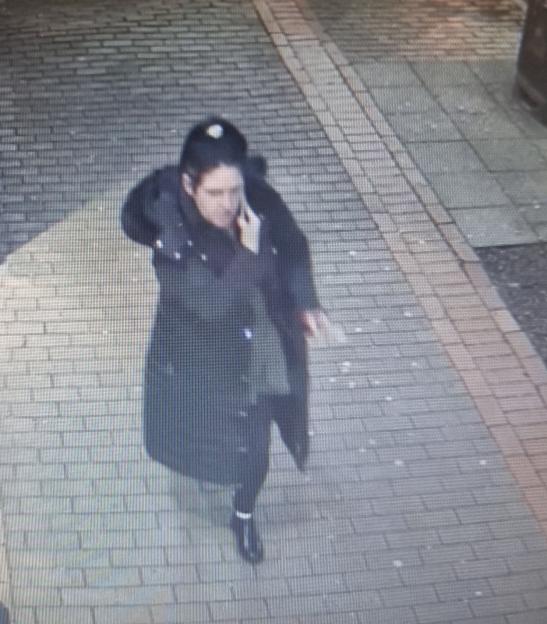 CCTV image of a woman, Kayleigh, in a dark coat walking and talking on a phone.