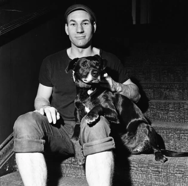 Actor Patrick Stewart sitting on a staircase with Blackie, a rescue dog cast as Crab in The Two Gentlemen of Verona.