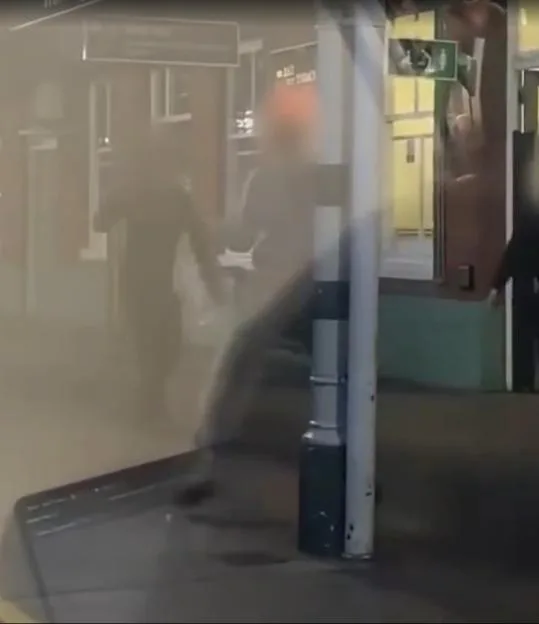 Machete-wielding youths brawl and swing blades at each other on a railway station platform.