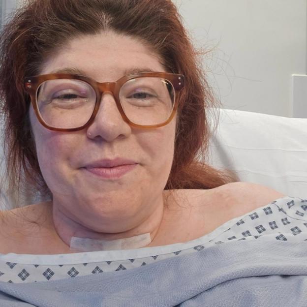 A woman with a bandage on her neck in a hospital bed.
