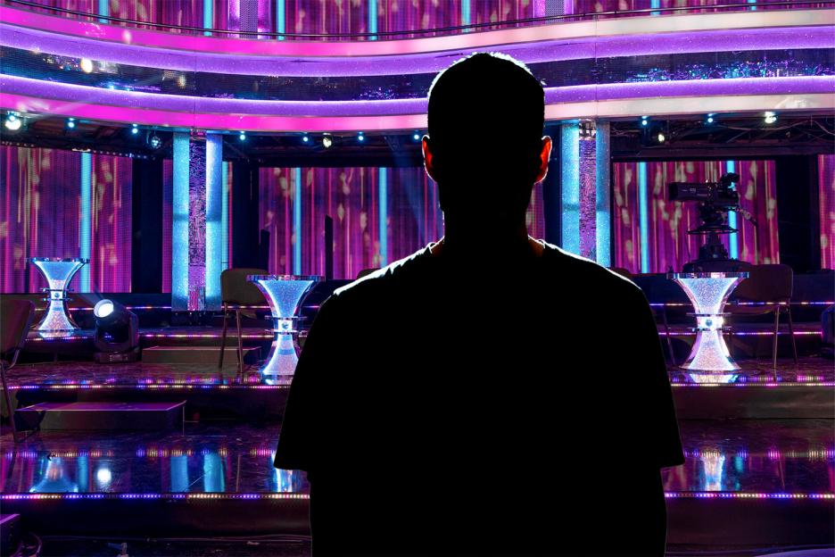 Silhouette of a person looking at an illuminated stage.