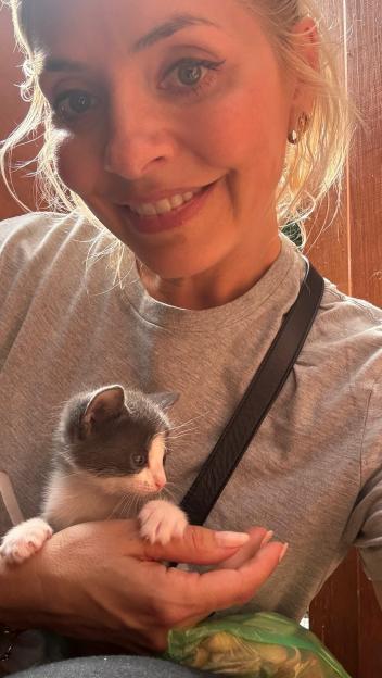 Holly Willoughby smiling and holding a kitten at an animal rescue.