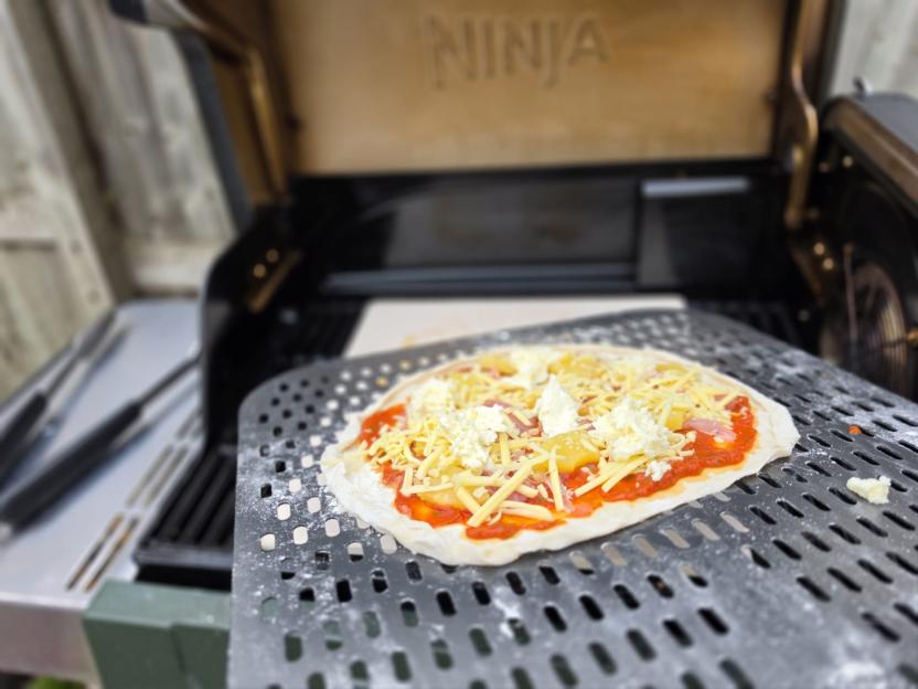 Pizza on a pizza peel ready to go into a Ninja grill.