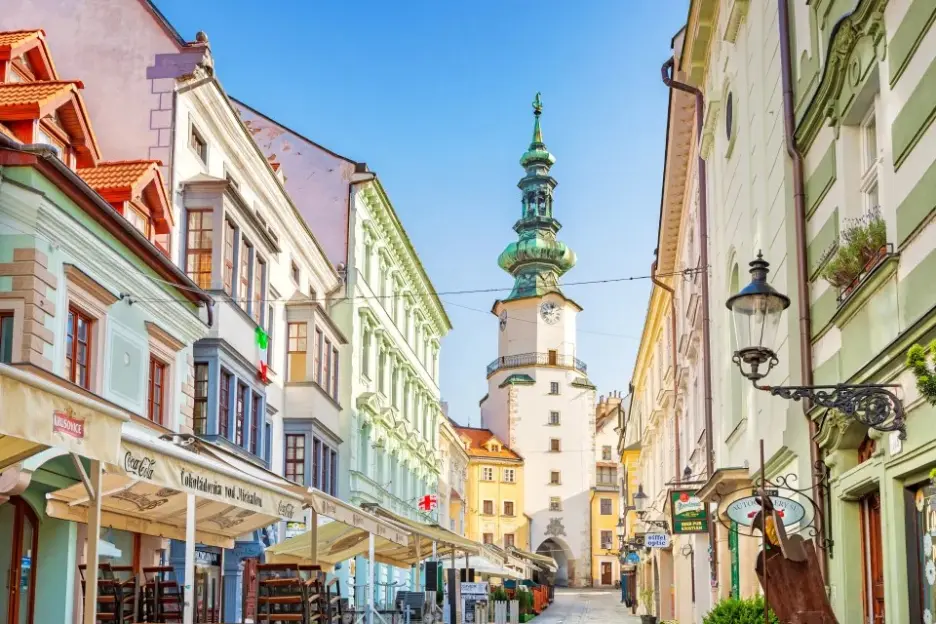 Alley of shops and restaurants leading to a clock tower.
