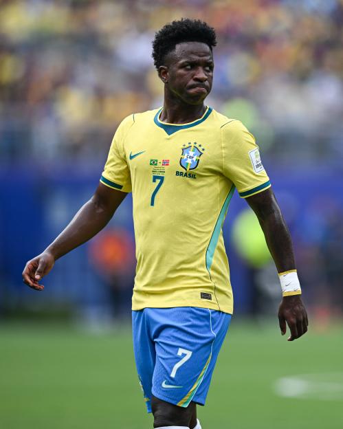 Vinicius Junior in a yellow Brazil jersey and blue shorts with the number 7, looking downfield during a soccer match.