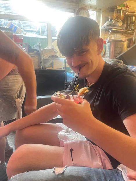 Tyler Kerry smiling and drinking a cocktail through a straw.