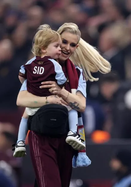A woman holding a young child in her arms at an Aston Villa match.