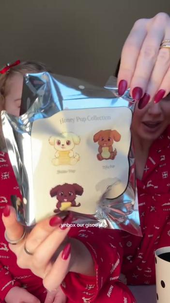 Two people in red pajamas opening a metallic package displaying the "Honey Pup Collection" with cartoon puppy illustrations.