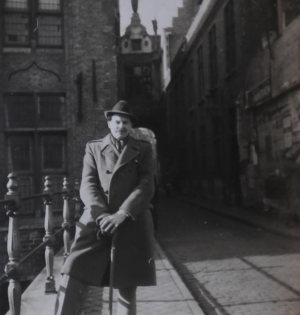 Robin Maudsley posing on a bridge with buildings and a street in the background.
