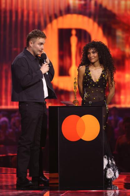 Olivia Dean (right) presents Sam Fender (left) with the 'Song of the year' award on stage at The BRIT Awards 2026.