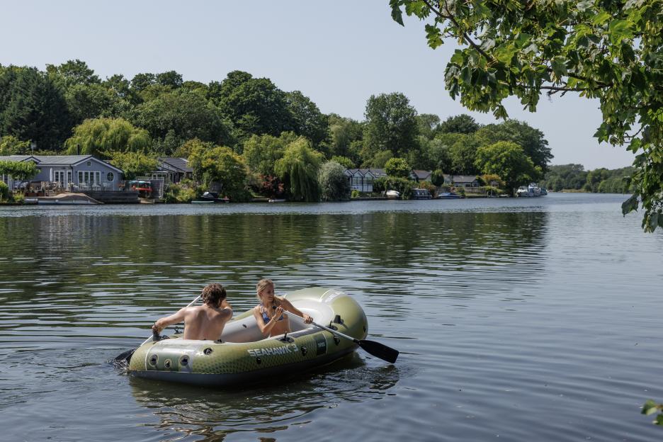 A man and woman paddling a rubber dinghy on the River Thames.