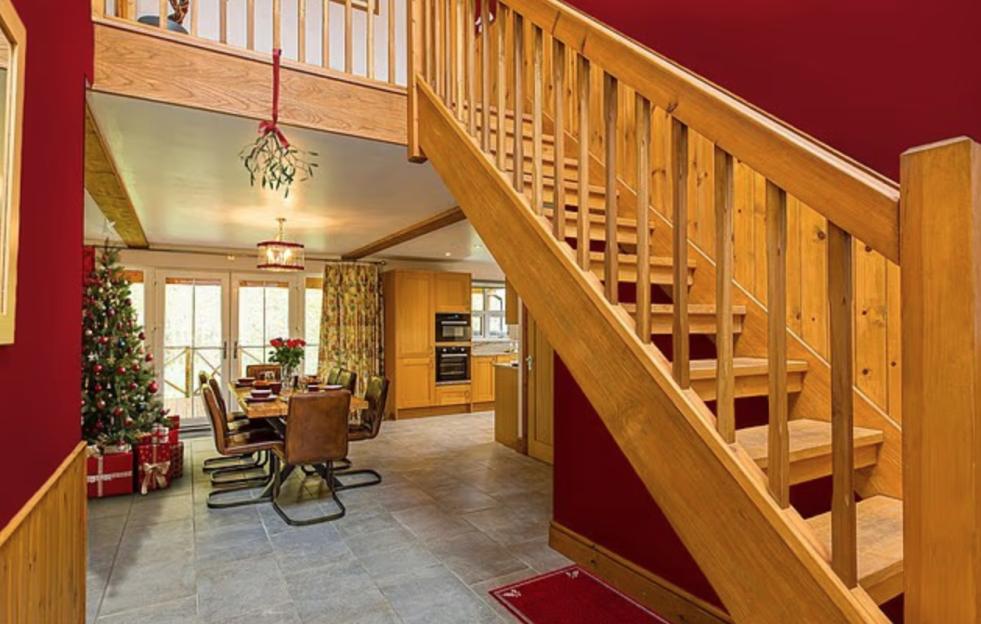 A Christmas-decorated holiday lodge with a dining area, a Christmas tree, and a staircase.
