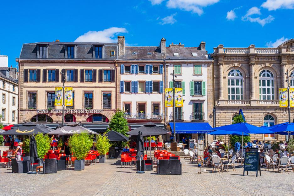 Saint-Corentin square in Quimper, France, with cafe tables and umbrellas set up in front of buildings.