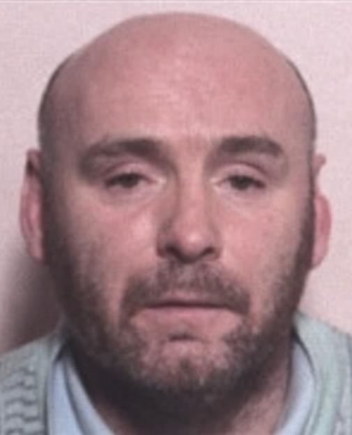 Mugshot of Derek McGraw Ferguson, a bald man with a beard and mustache, wearing a light-colored collared shirt.