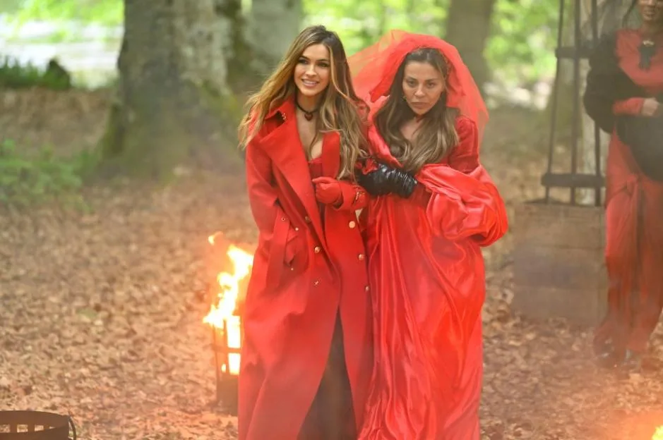 Chrishell Stause and Dolores Catania walk in a forest for "The Traitors," dressed in red.
