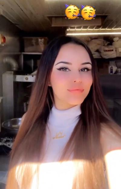 Nadia Yusuf, 17, with long dark brown hair, wearing a white turtleneck top, with two party-blower emojis above her head.