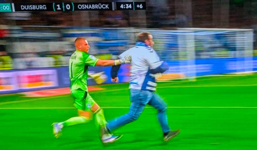 'Intense Showdown: Players Restrain Furious Pitch Invader Charging at Referee'