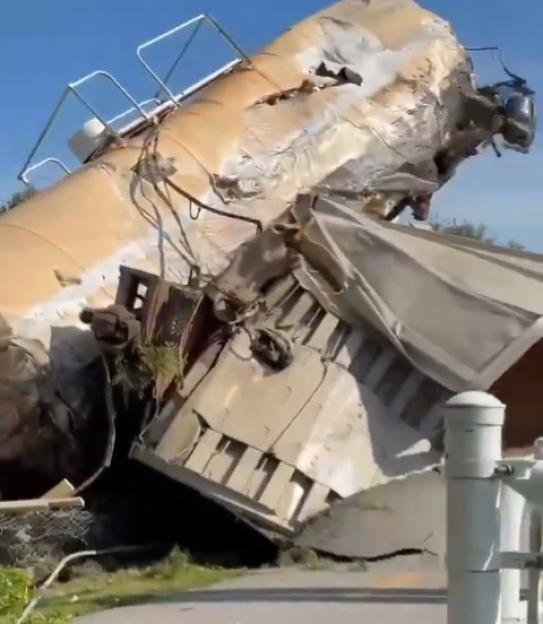 Damaged train cars derailed and tilted on their sides.