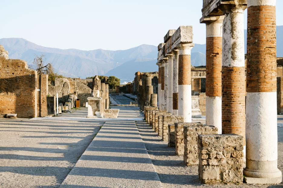 Ruins of ancient Roman buildings in Pompeii, with Mount Vesuvius in the background.