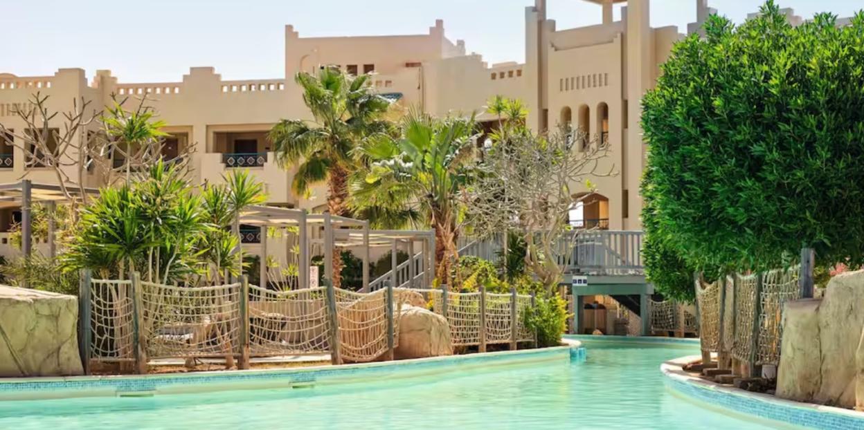 A resort with a lazy river winding through palm trees and buildings.