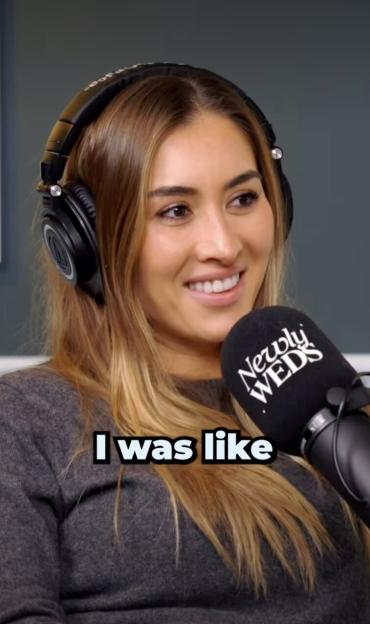 Sophie Habboo smiling and wearing headphones while speaking into a "Newly Weds" microphone.