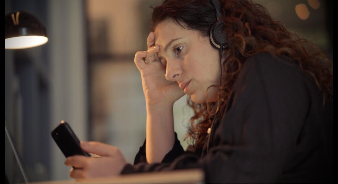 Nina Morgan, Megan's sister, wearing headphones and looking at a phone.