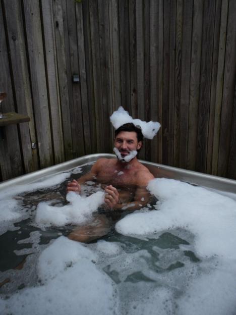 Man with a foam beard and foam "ears" in a hot tub.