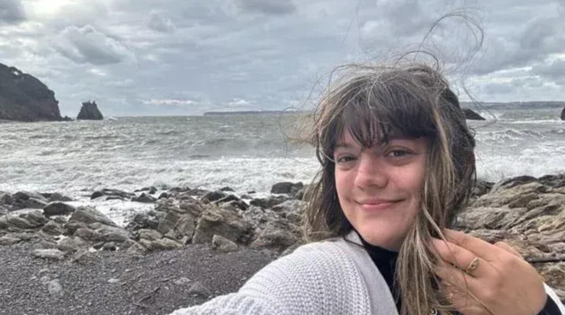 Cyann Fielding smiling at the camera with the English Riviera coastline in the background.