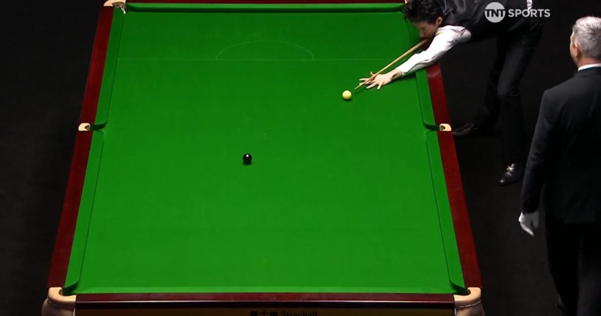 A snooker player aiming for a yellow ball on a green table, with a referee standing nearby.