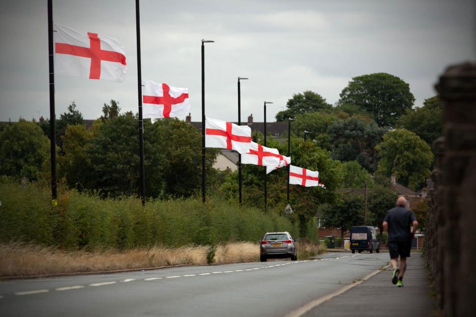 Cars drive past St George flags on lampposts in Bartley Green, Birmingham.