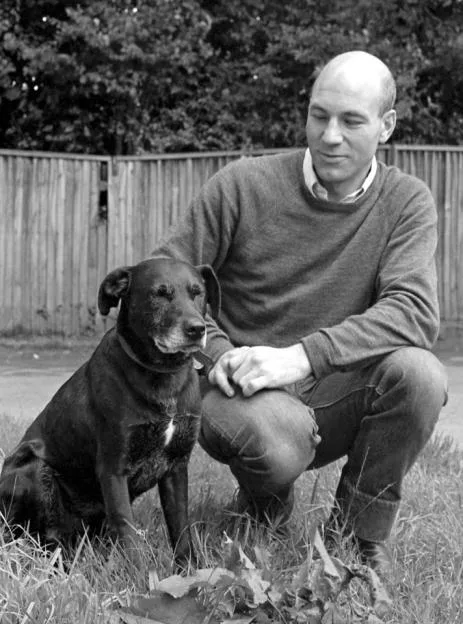 Patrick Stewart crouches in the grass next to his dog, Crab.