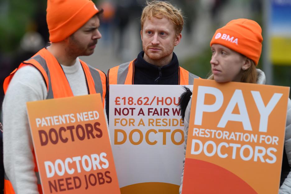 Resident doctors and supporters picket outside St Thomas' hospital with signs during a 5-day strike over pay in London.