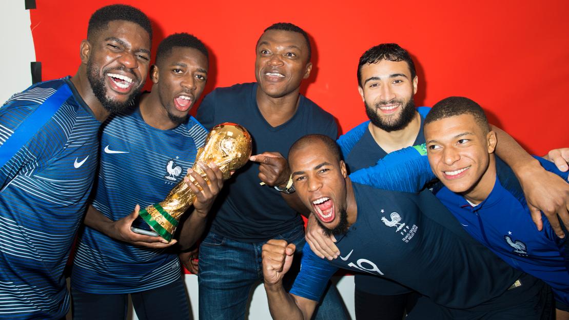 French soccer players posing with the FIFA World Cup trophy.