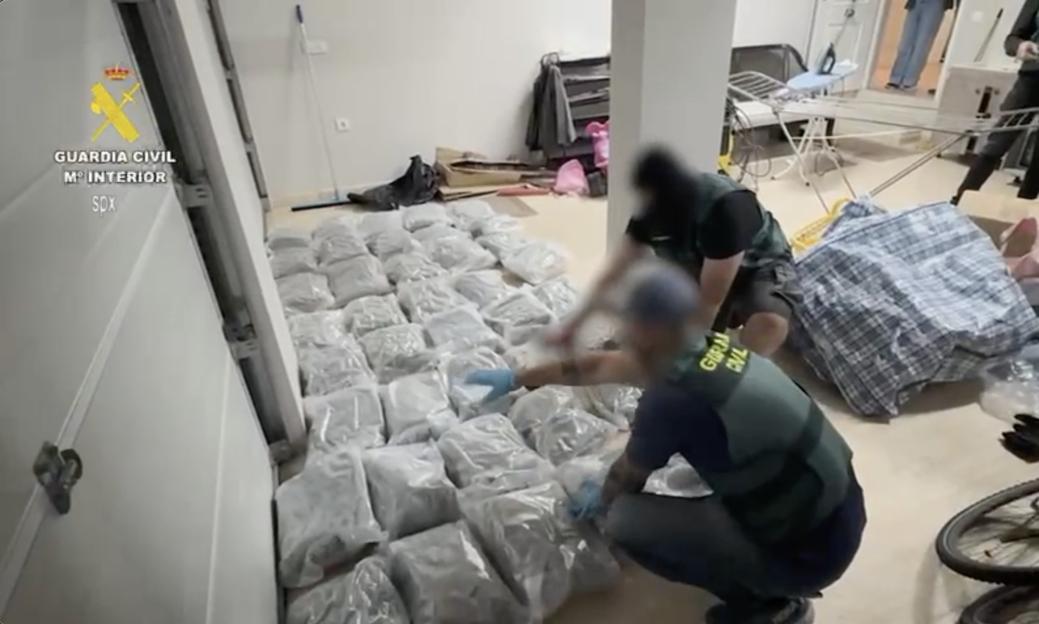 Police officers inspecting bags of drugs during a raid.