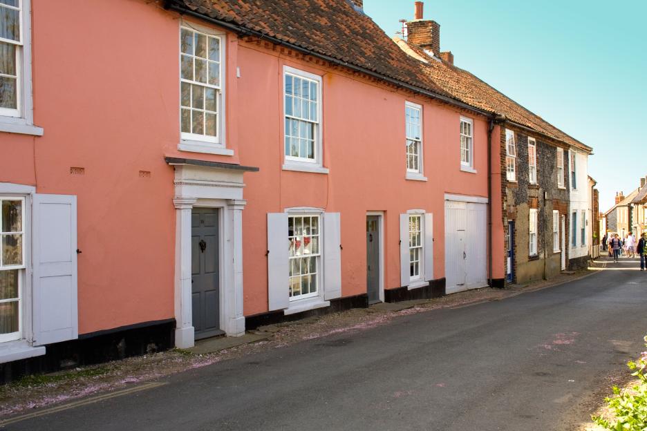 Pink houses and cottages lining a street in the seaside village of Blakeney, Norfolk.