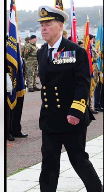 Man dressed as a Rear Admiral wearing a cap and medals on his black uniform.