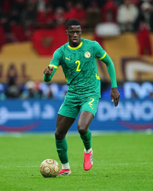 A soccer player in a green jersey with the number 2 on it dribbles the ball.