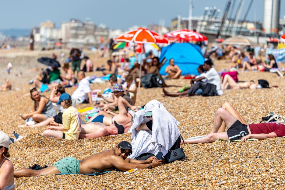 People relaxing on a pebble beach under clear skies.