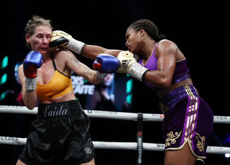 Two female boxers in the ring, one in yellow and blue punching the other in purple and gold in the face.