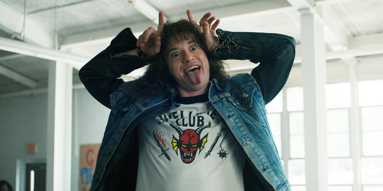 Joseph Quinn as Eddie Munson in Stranger Things, making a silly face with his tongue out and hands forming horns.