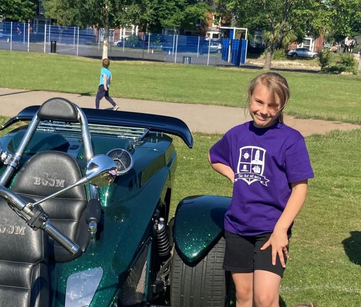 Lilia Valutyte, 9, in a purple shirt standing next to a green custom motorcycle.