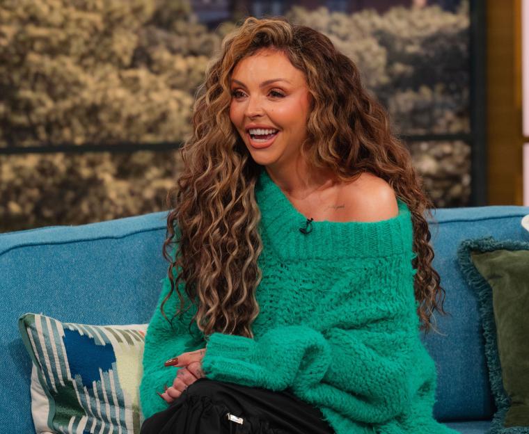 Jesy Nelson sitting on a blue sofa and laughing during a TV appearance on 'This Morning.'