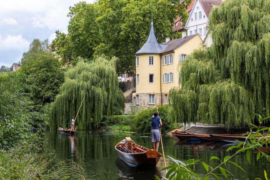 Two people punting on the Neckar river near Hoelderlinturm in Tuebingen, Germany.