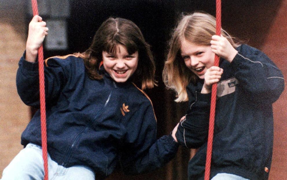 Jessica Chapman and Holly Wells smiling while holding onto red ropes, possibly on a swing.