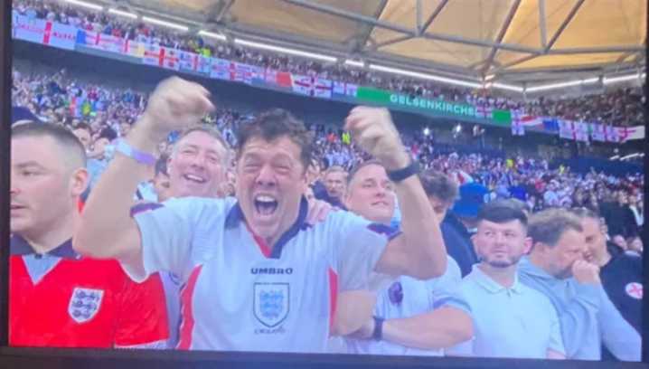 a man in a umbro shirt is screaming in a crowd