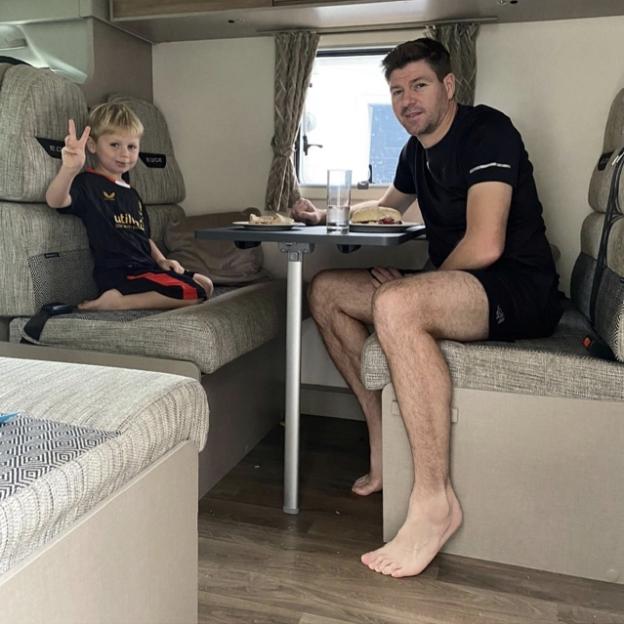 A man and a young boy eating at a table inside an RV.