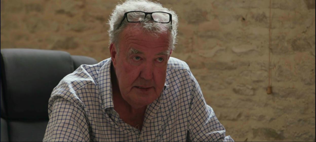 Jeremy Clarkson wearing a blue and white checkered shirt, glasses perched on his head.