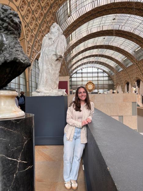 Woman standing in Paris museum near sculptures.