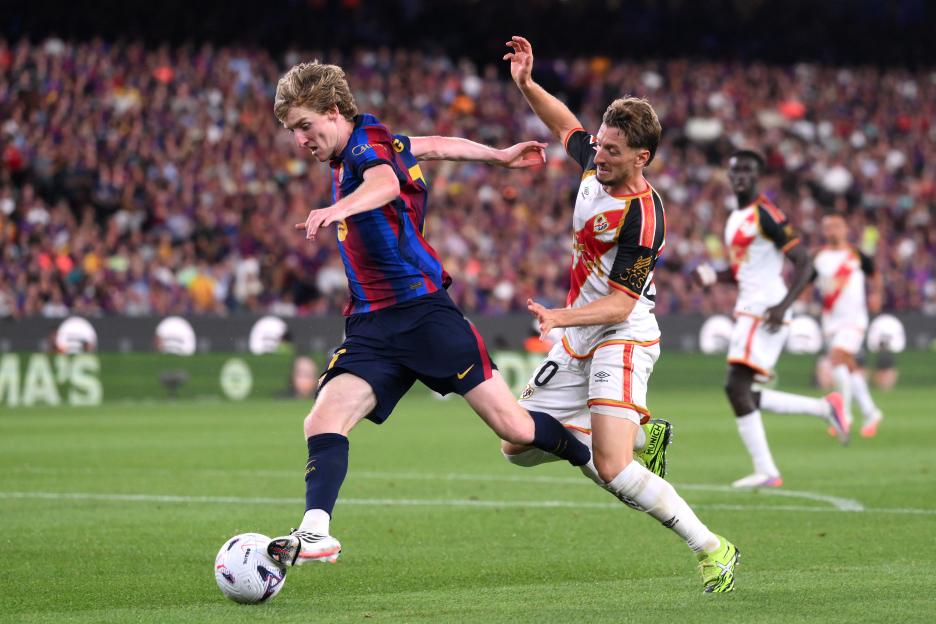 Anthony Gordon of Barcelona runs with the ball under pressure from Ivan Balliu of Rayo Vallecano during a soccer match.