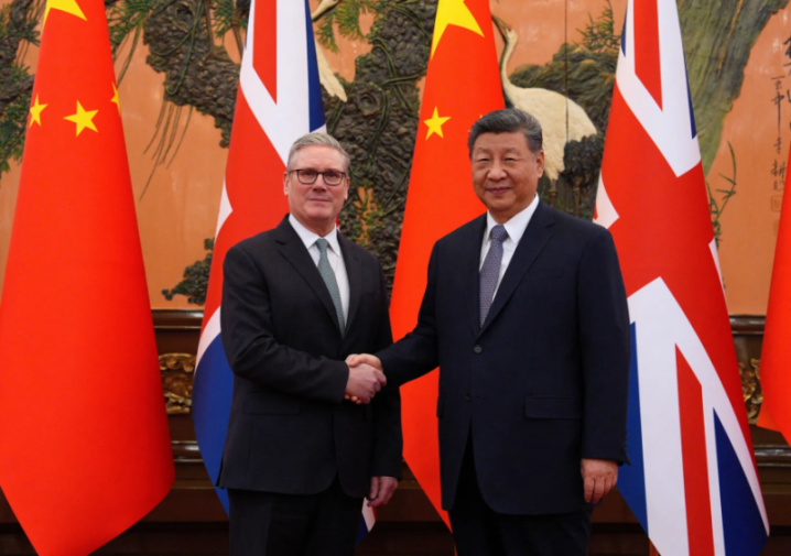 Two men, Xi Jinping and Keir Starmer, shake hands in front of Chinese and British flags.